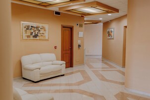 A hallway with a white sofa, a wooden door, and two framed artworks on the walls.