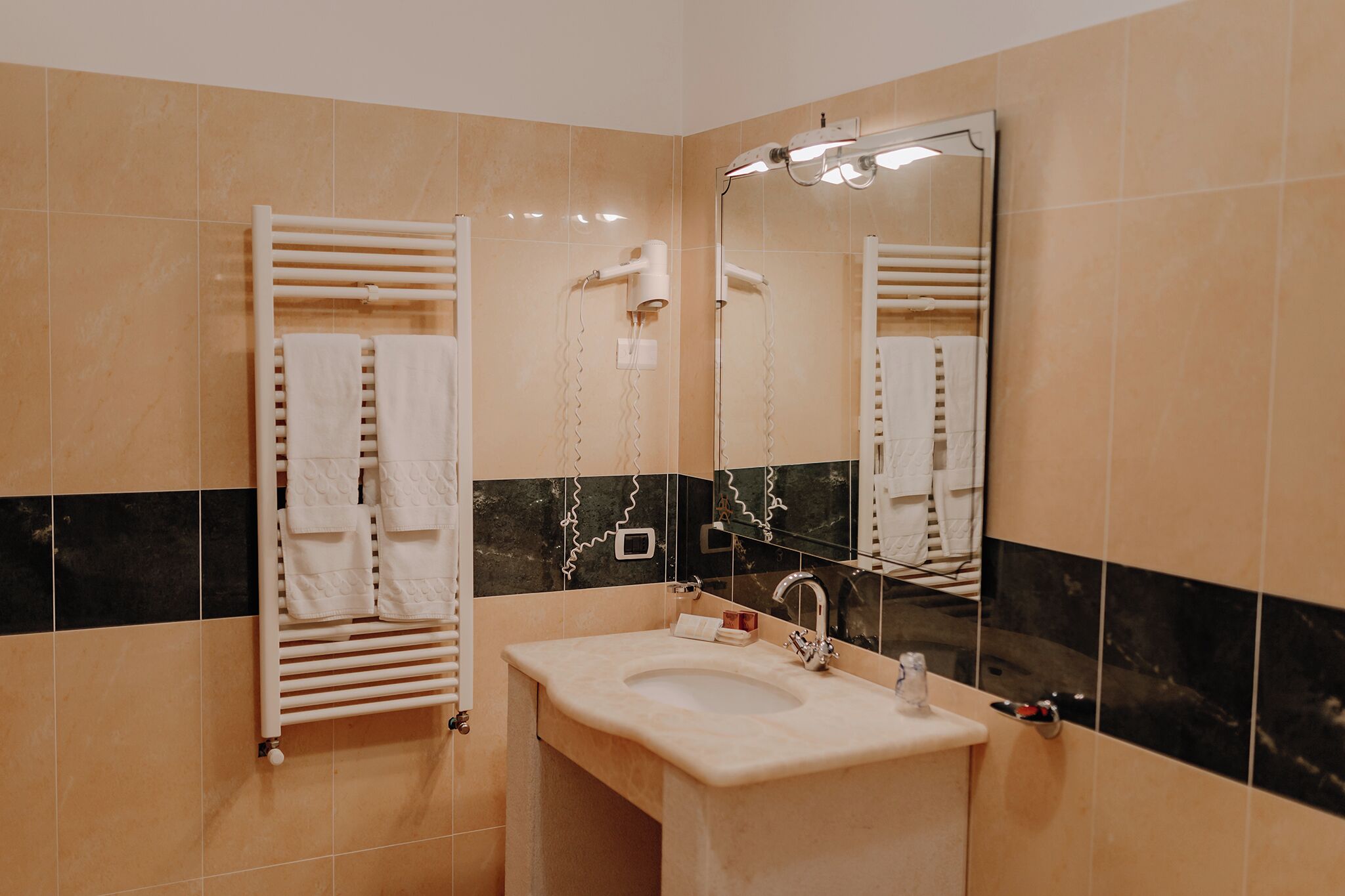Un baño con lavamanos, espejo, toallero y secador de pelo.