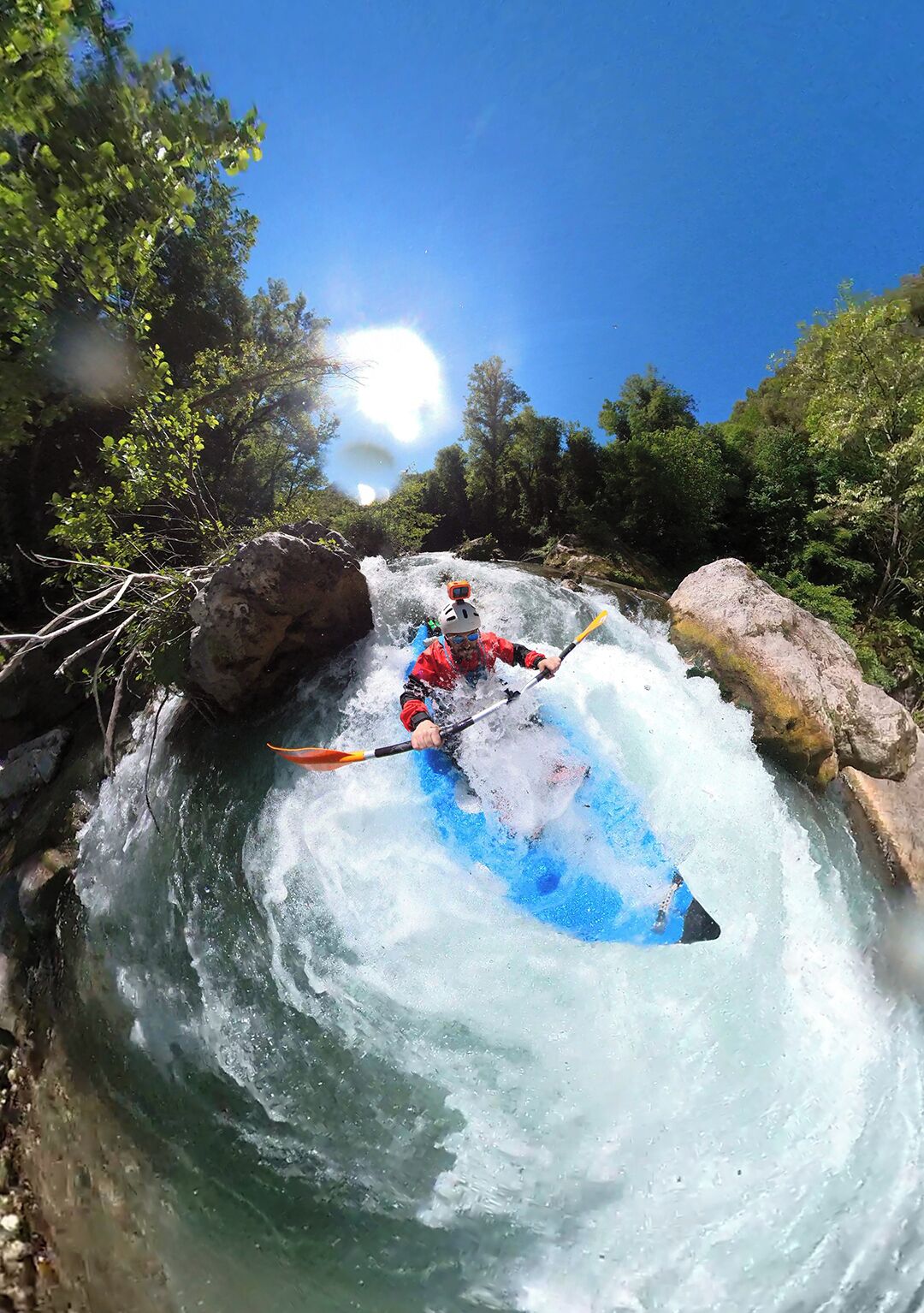 A kayaker navigating a rapid in a forested area.