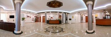 A spacious lobby with a reception desk, multiple columns, and a decorative ceiling.