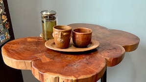 Een houten tafel met een rustieke afwerking, met twee zwarte stoelen en een geweven vloerkleed.