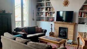 Een woonkamer met een bank, een open haard, een boekenkast en een televisietoestel.