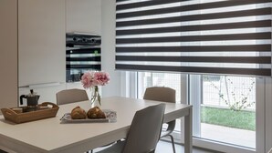 A modern kitchen with a white countertop, a coffee maker, a vase with flowers, and a plate with pastries.