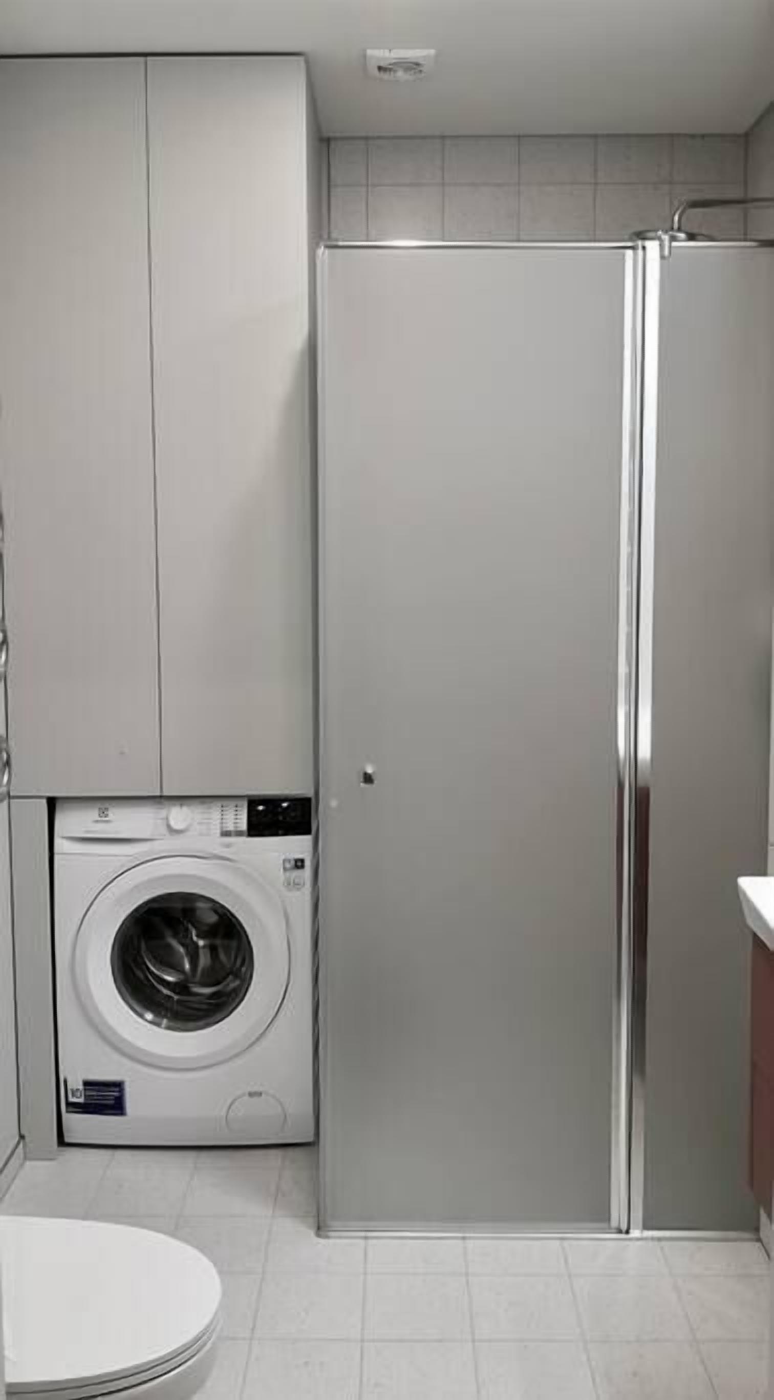 Une petite buanderie équipée d’un lave-linge, de toilettes et d’un réfrigérateur.