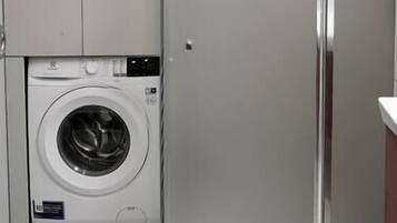 A compact laundry room with a washing machine, a toilet, and a refrigerator.