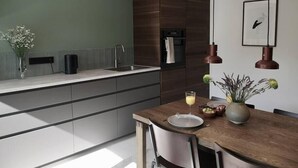 Una cocina moderna con una mesa de comedor de madera, horno empotrado y una lámpara colgante.