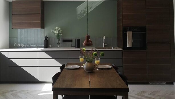 Una cocina moderna con una mesa de comedor de madera, iluminación colgante y vistas al área de estar.
