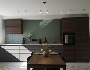 Una cocina moderna con una mesa de comedor de madera, iluminación colgante y vistas al área de estar.