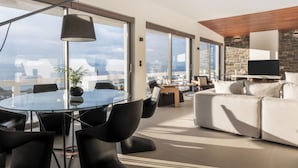 A modern living room with a glass table, black chairs, a sofa, and a TV. - Villa Vel Aegina (Aegina)