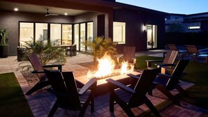 A modern house with a fire pit, outdoor seating, and a patio area.