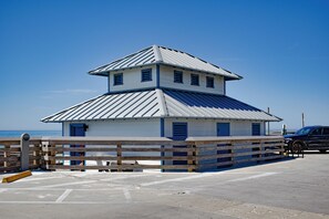 A two-story building with a metal roof and blue accents, located near a body of water. - Beach House, Private Pool, Water view, Sleeps 12, Golf Cart (Destin)