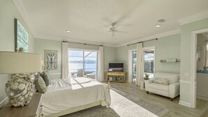 A spacious bedroom with a large bed, a television, and a view of the outdoors.