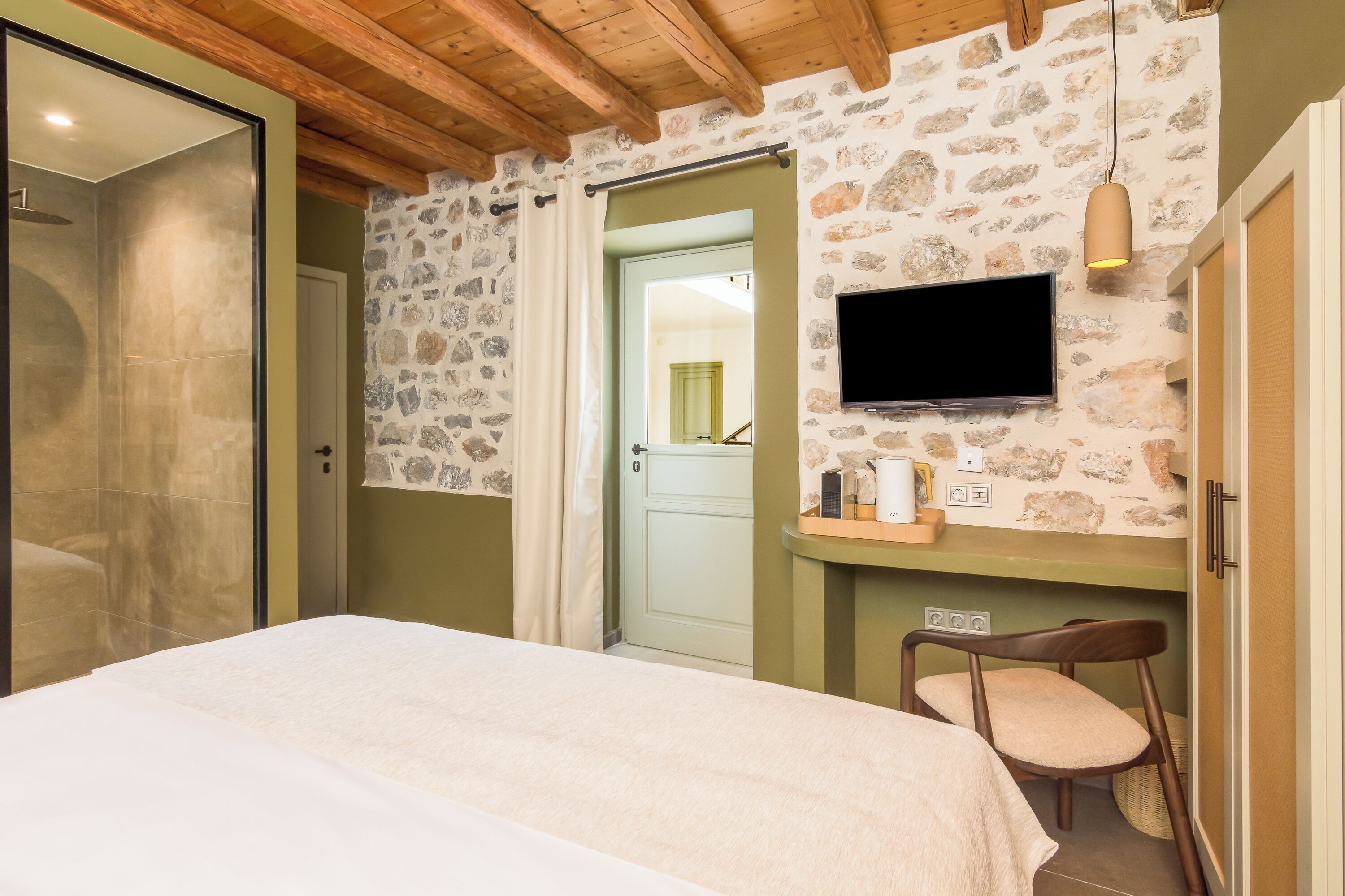 Een slaapkamer met een stenen muur, een bed, een televisie en een stoel.