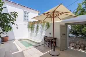 Un patio con piscina, una mesa con sillas y una puerta.