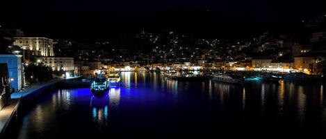 A nighttime view of a harbor with boats and illuminated buildings.