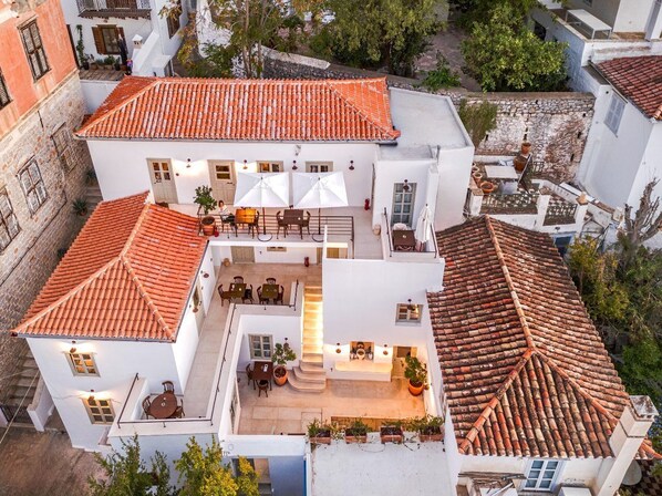Un edificio blanco con techo de tejas rojas, un patio central con asientos y una escalera que conduce a un nivel superior.