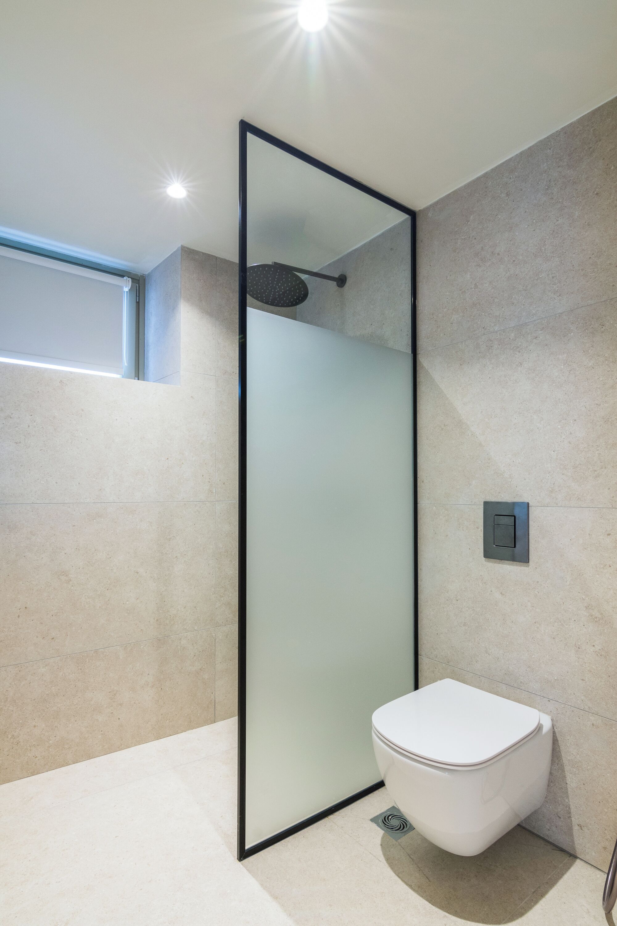 A modern bathroom with a glass partition, a white toilet, and a shower area.