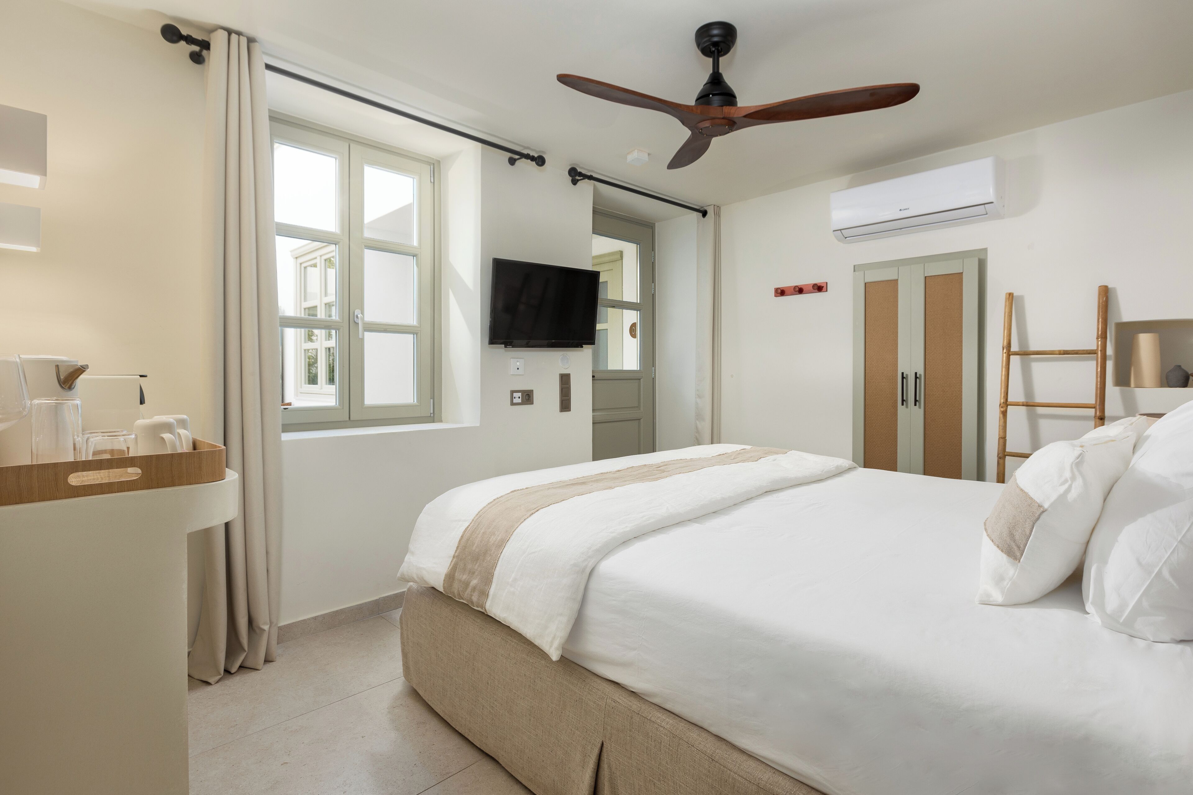 Et hotelværelse med seng, skrivebord, fjernsyn, aircondition og et garderobeskab.