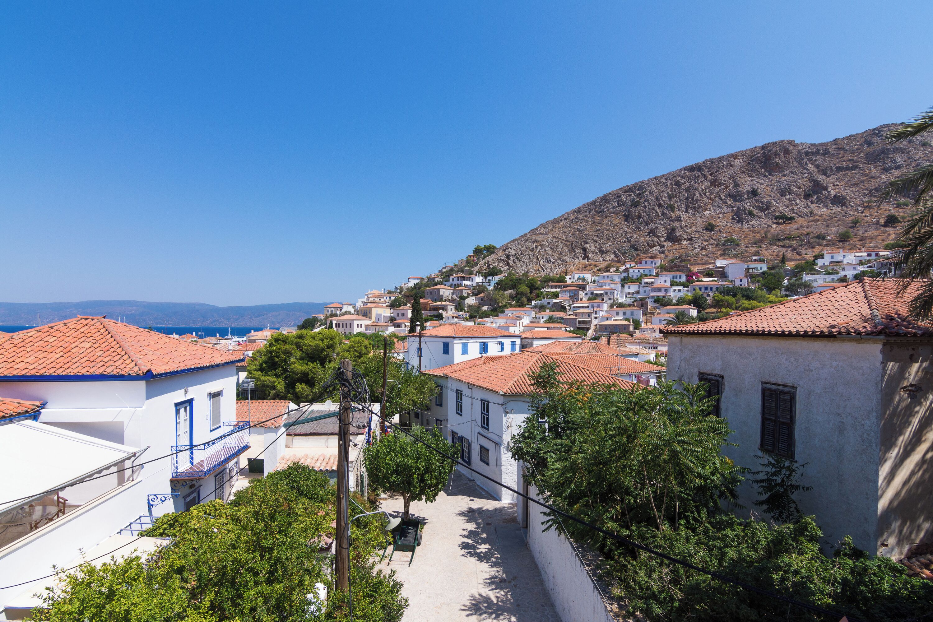 A coastal village with white buildings and red-tiled roofs, narrow streets, and a hillside backdrop.