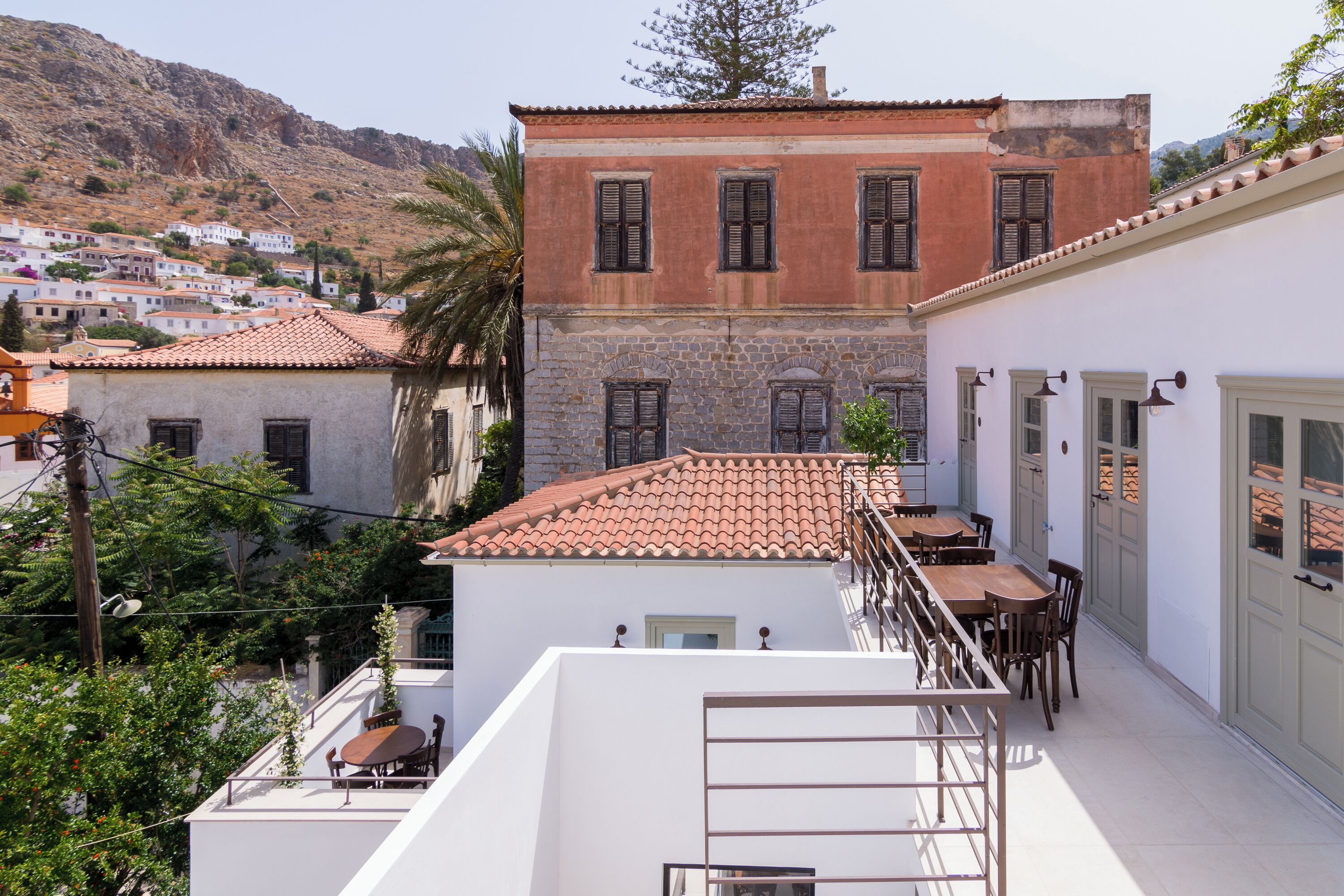 Terraza en la azotea con mesa y sillas, con vistas a una colina y edificios tradicionales.