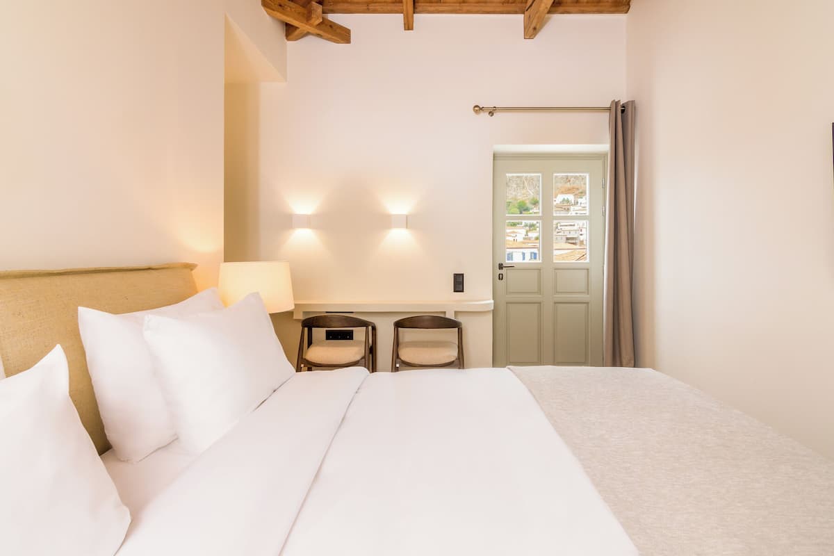 Une chambre à coucher avec un lit, deux chaises, un bureau et une porte.