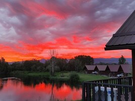 Vista de un lago con atardecer, reflejando tonos vibrantes de rojo y rosa en el cielo.