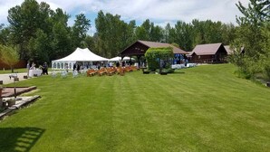 A grassy outdoor area with a white tent, wooden tables, and a covered seating area. - SkyWater Cabins (Hamilton)