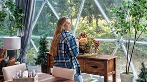 Una habitación amplia con un gran ventanal, una mesa de madera, sillas, una lámpara y una planta en maceta.