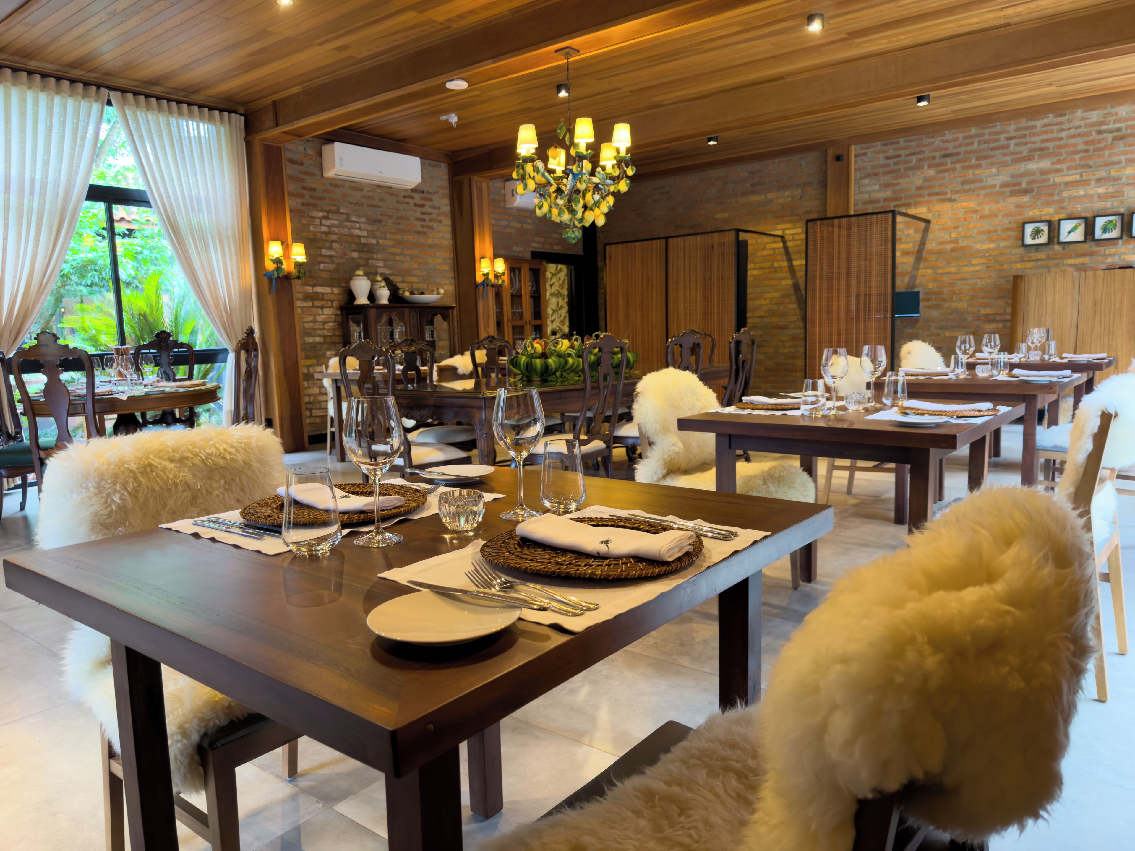 A dining area with wooden tables, white fluffy chairs, and a chandelier.