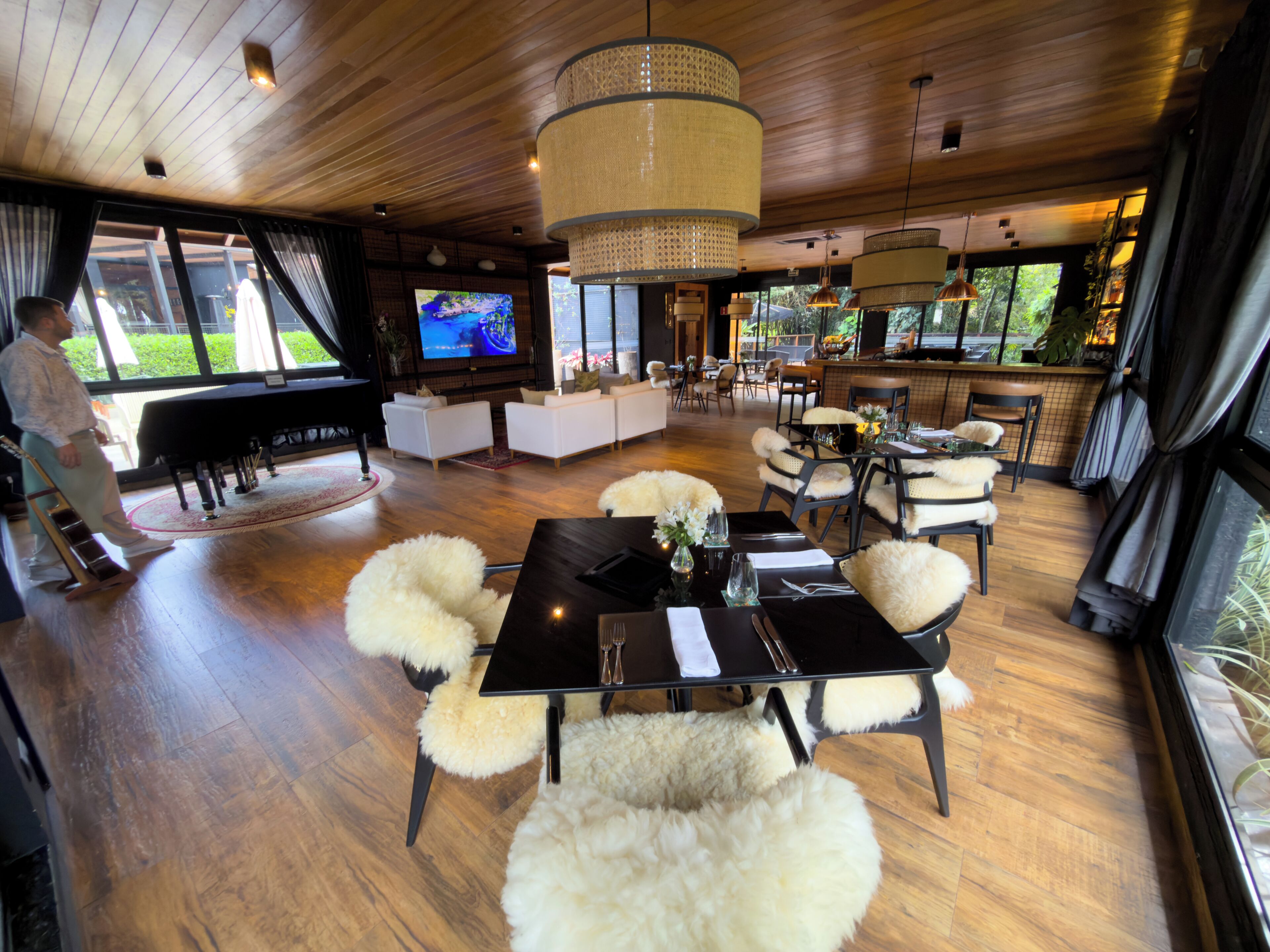 A spacious living area with a piano, sofas, a dining table with chairs, and a TV.