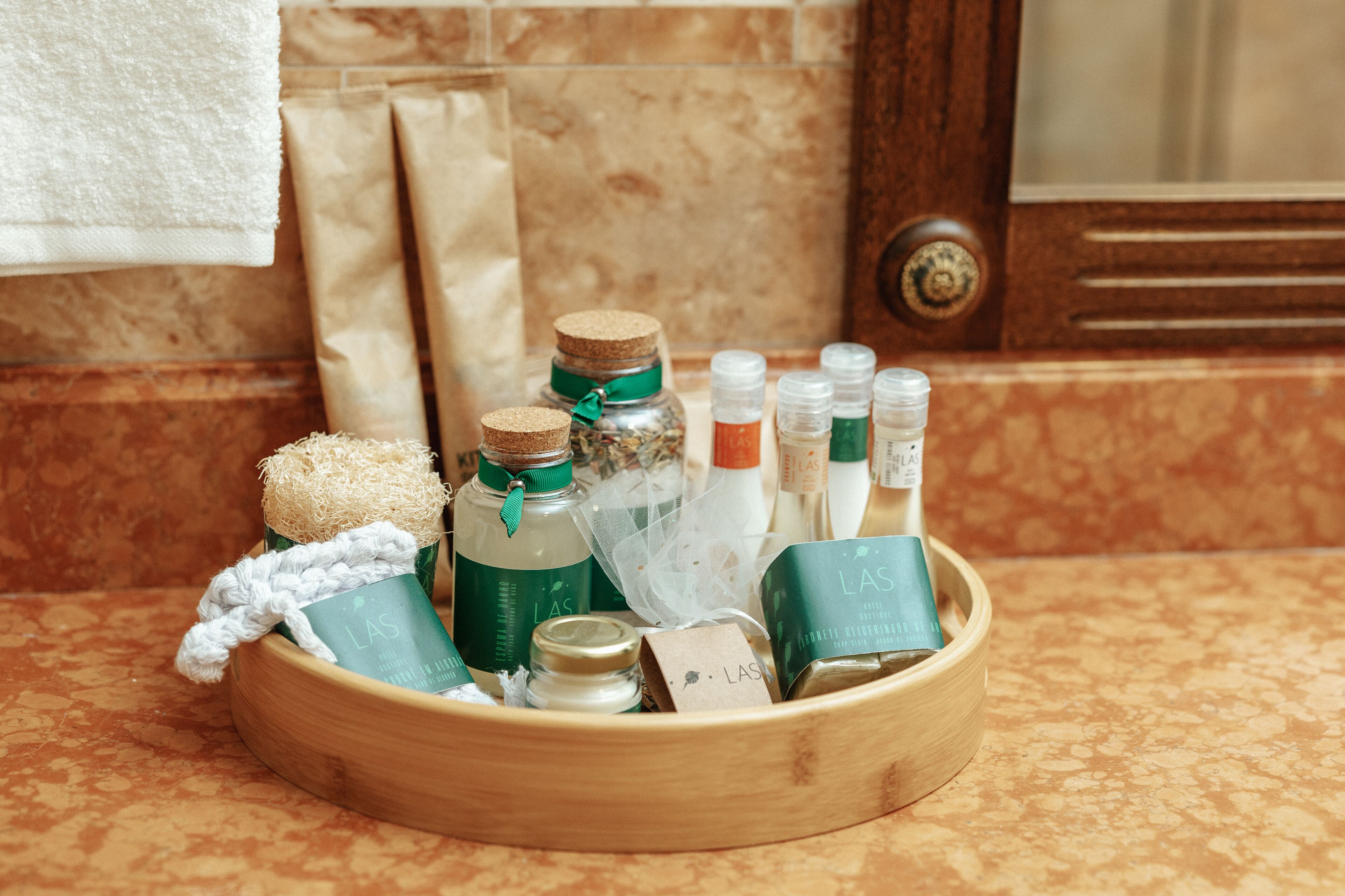 Un plateau en bois contenant divers articles de toilette, posé sur le comptoir d’une salle de bain.