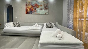 Une chambre d’hôtel moderne avec un grand lit, un canapé-lit et un tableau au mur.