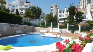 Piscina con sillas de descanso, rodeada de un muro de piedra y follaje.