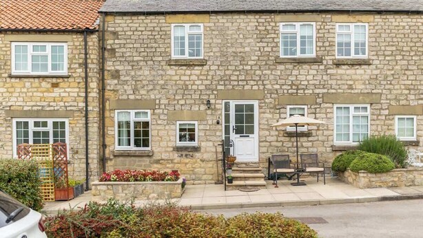 A stone building with a white door, windows, and outdoor seating. - Between Coast & Moors • Pickering 2BR • Sleeps 4 (Pickering)