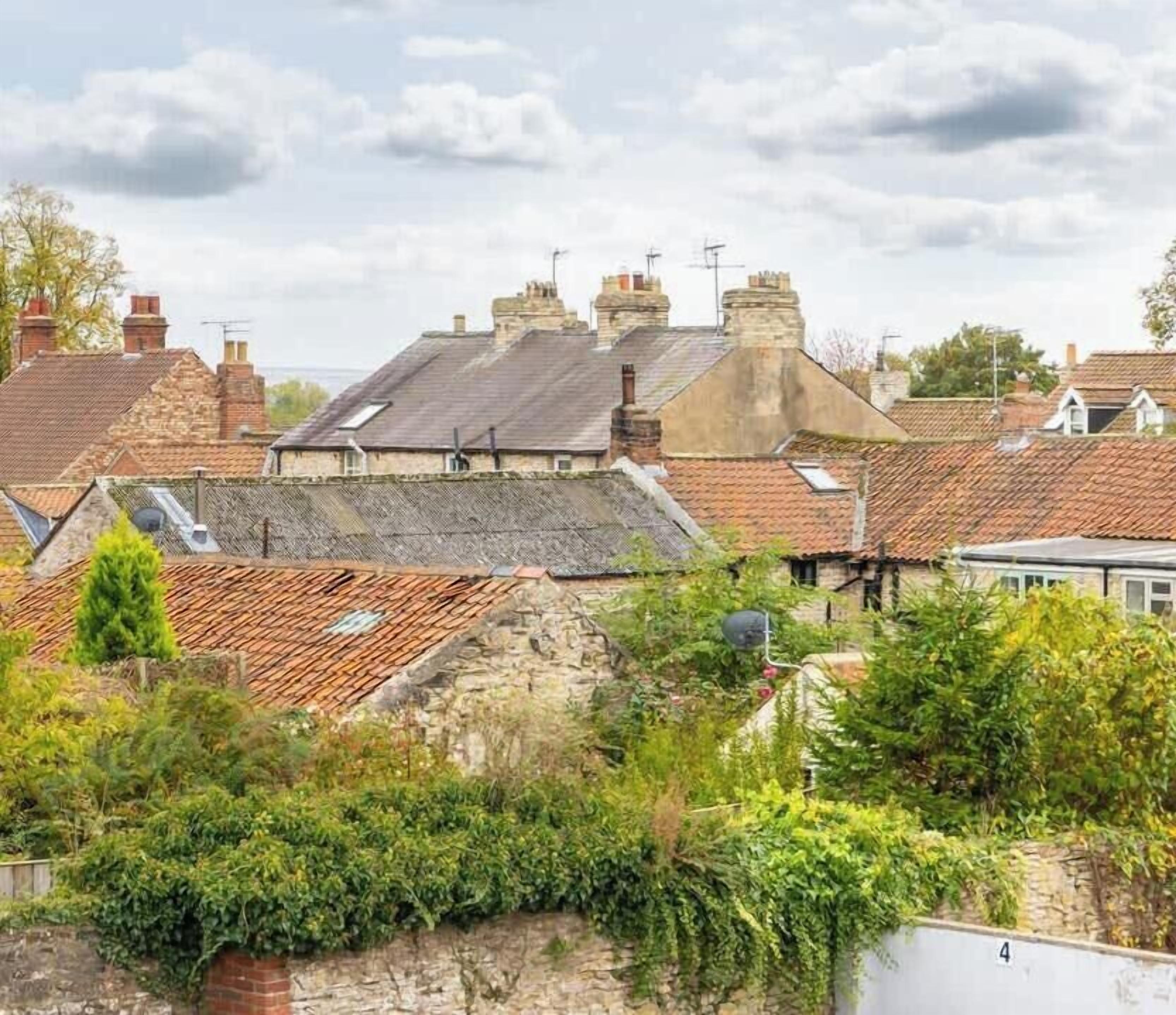 A residential area with stone houses, red-tiled roofs, and a stone wall.