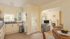 A kitchen with cabinets, a sink, and a trash can. There is a dining area with a table and chairs. - Between Coast & Moors • Pickering 2BR • Sleeps 4 (Pickering)
