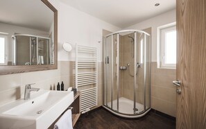 Une salle de bain moderne avec une douche, un lavabo et un miroir.