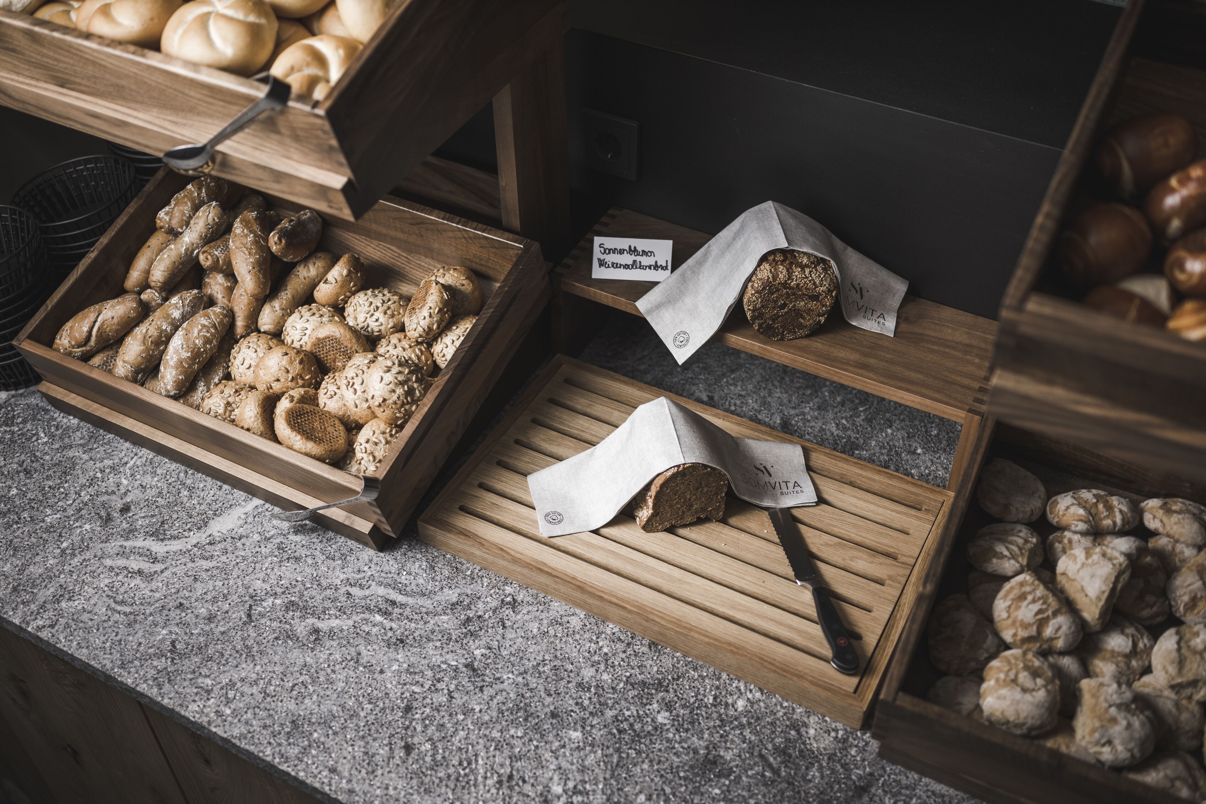 A bakery display with various types of bread and pastries in wooden crates.