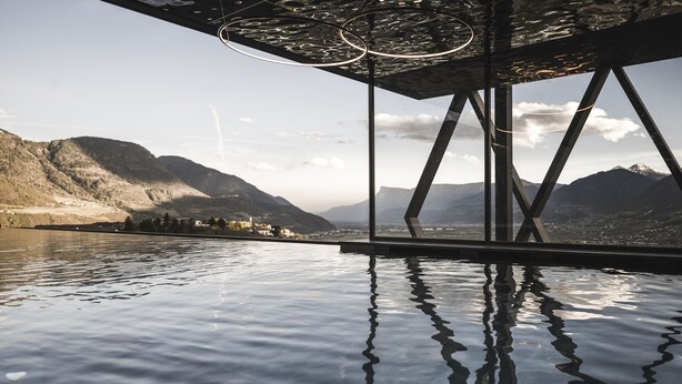Un interior moderno con un amplio ventanal que ofrece vistas a un paisaje montañoso y una masa de agua.