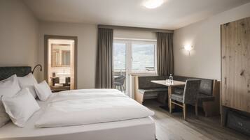 Habitación de hotel con cama, escritorio, silla, ventana con cortinas y vistas al exterior.