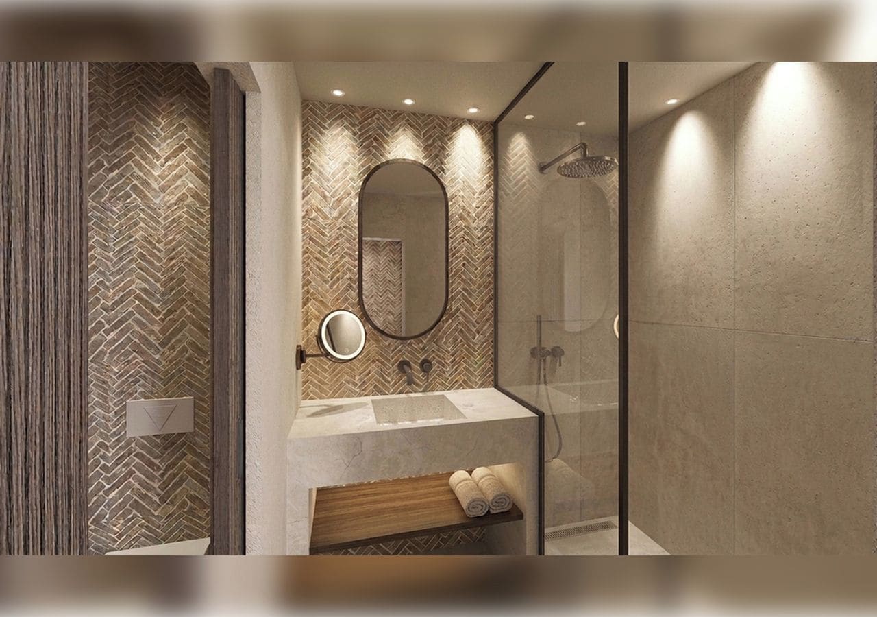A modern bathroom with a herringbone patterned wall, a rectangular sink, a mirror, and a glass-enclosed shower area.