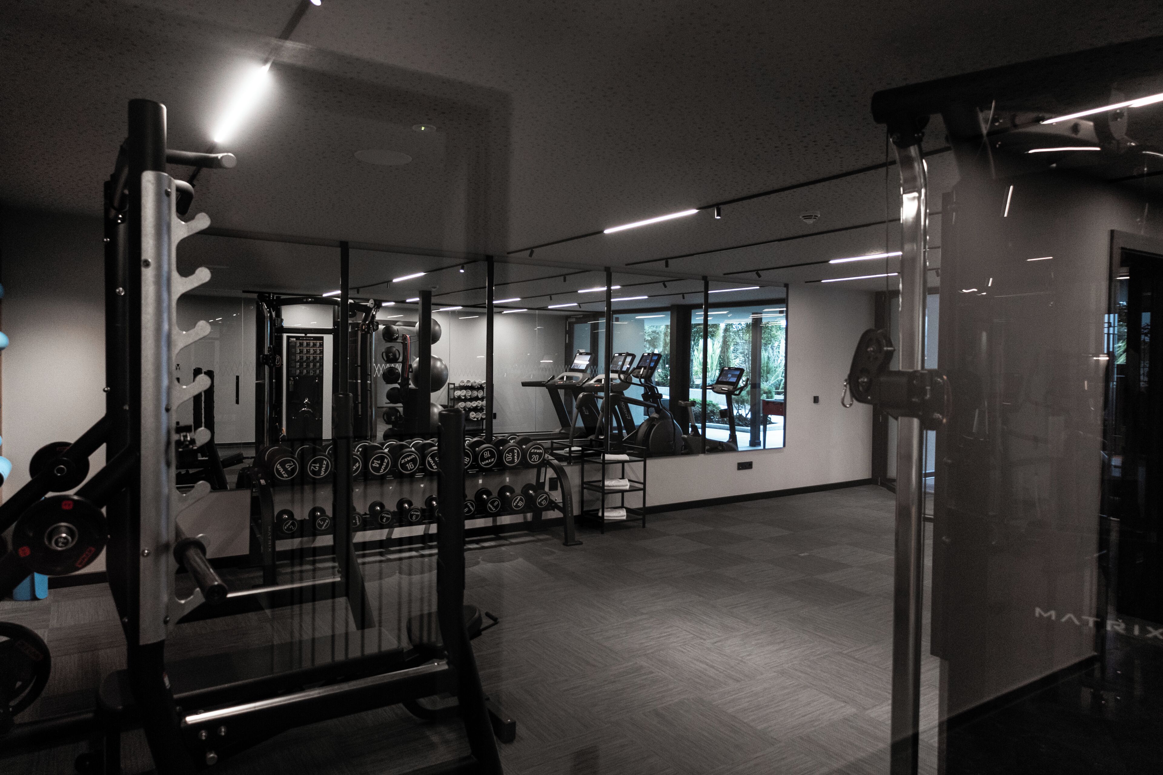 Ett gym med träningsutrustning, en stång för vikter och ett löpband.