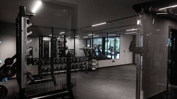 Ett gym med träningsutrustning, en stång för vikter och ett löpband.