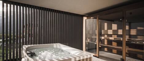 Ein modernes Badezimmer mit einer freistehenden Badewanne, einer Duschkabine aus Glas und Blick ins Freie.