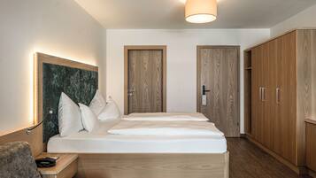 A modern bedroom with a wooden bed, a nightstand, a headboard, and a wardrobe.