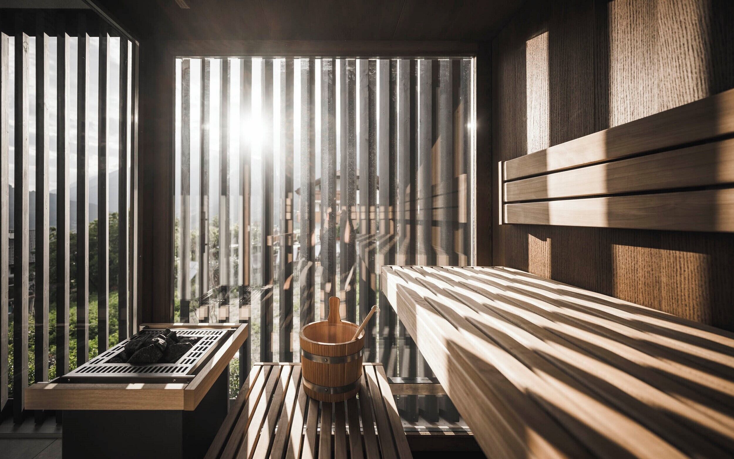 A sauna room with a wooden bench, a wooden bucket, and a small table with a towel.