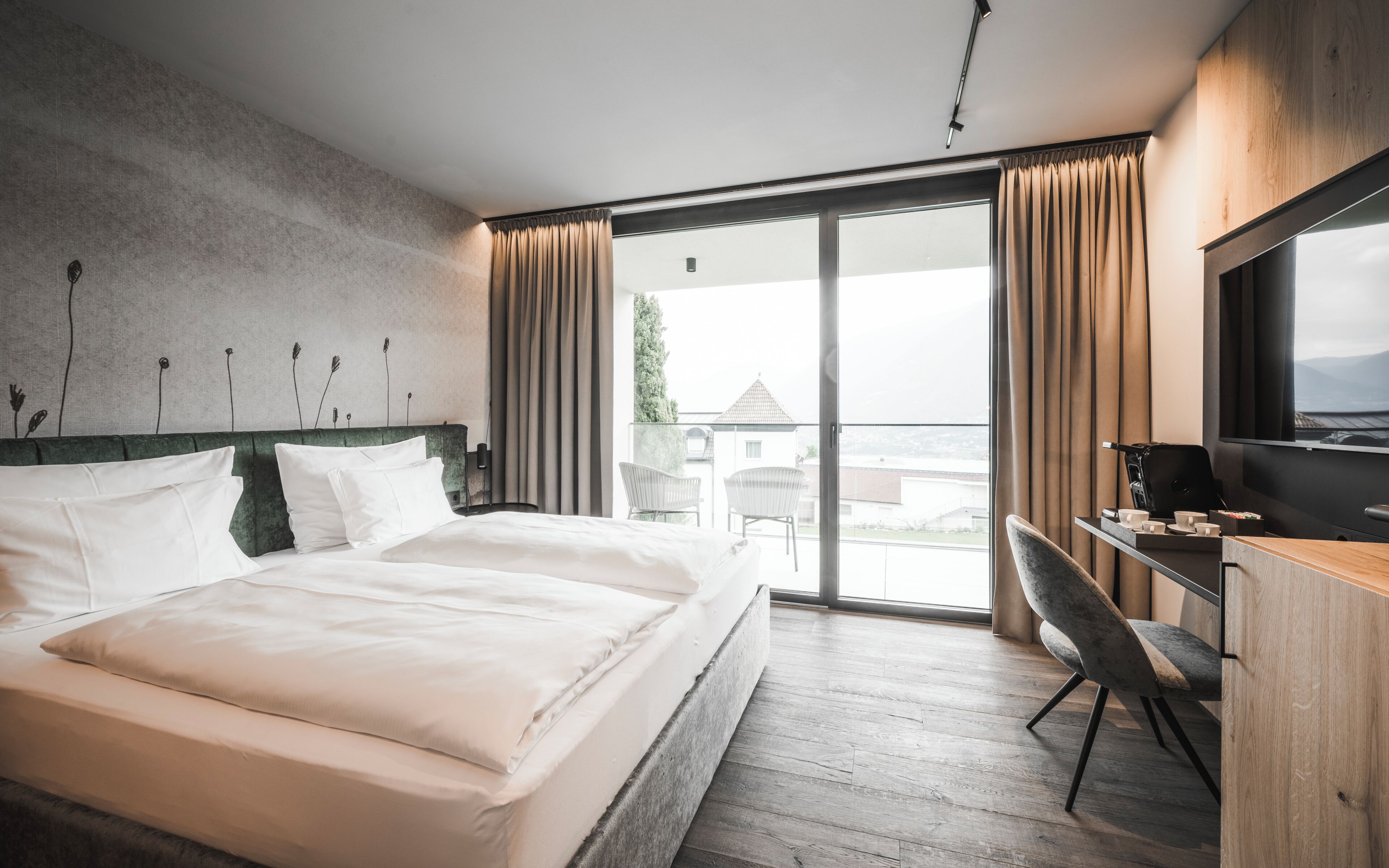 A hotel room with a bed, a desk, and a view of the outside.