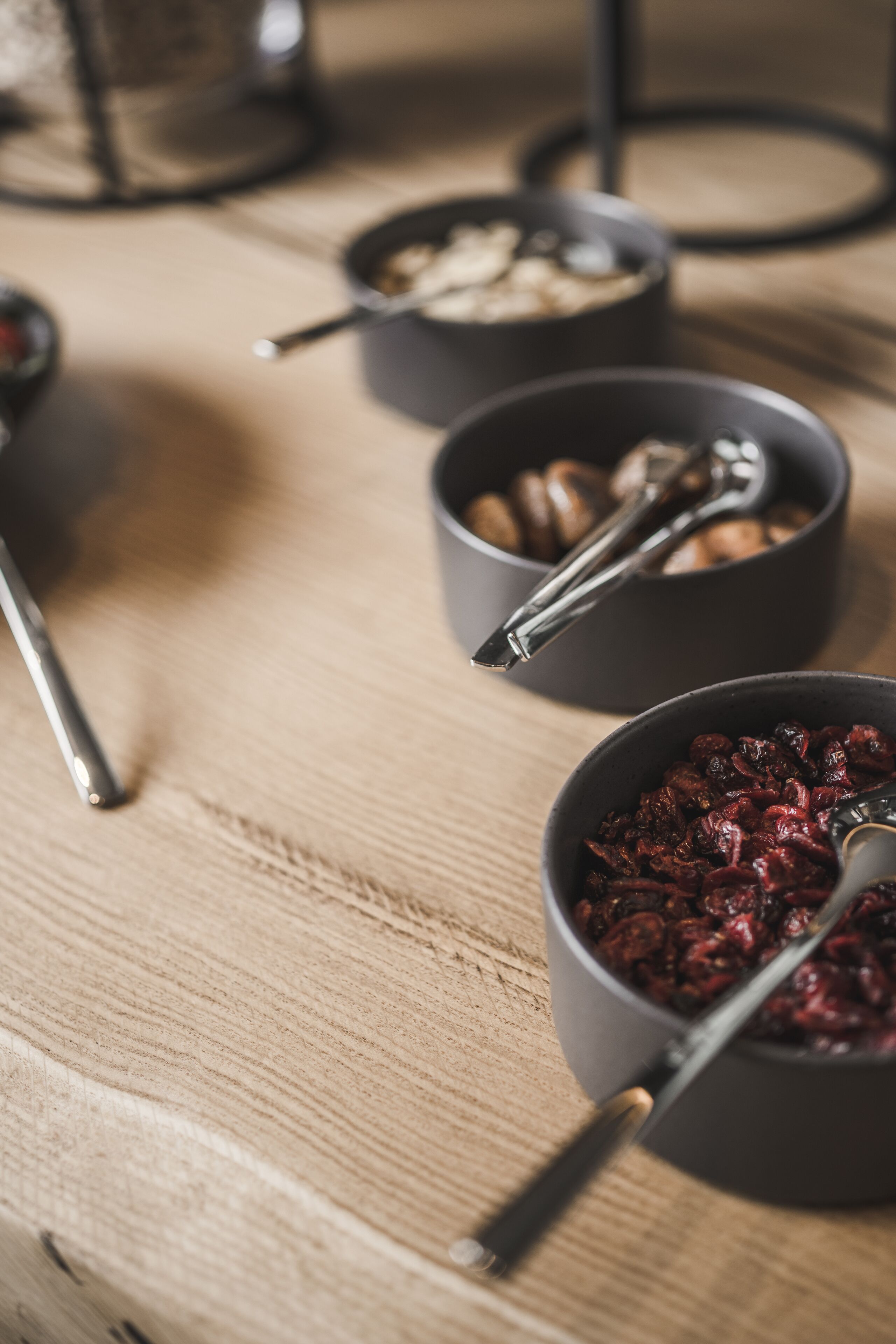 Three bowls of food on a wooden table.