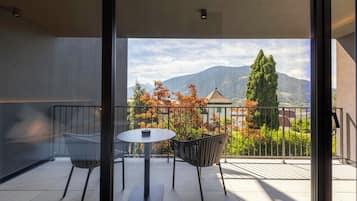Un balcón con mesa y sillas, con vistas al follaje otoñal y a las montañas.