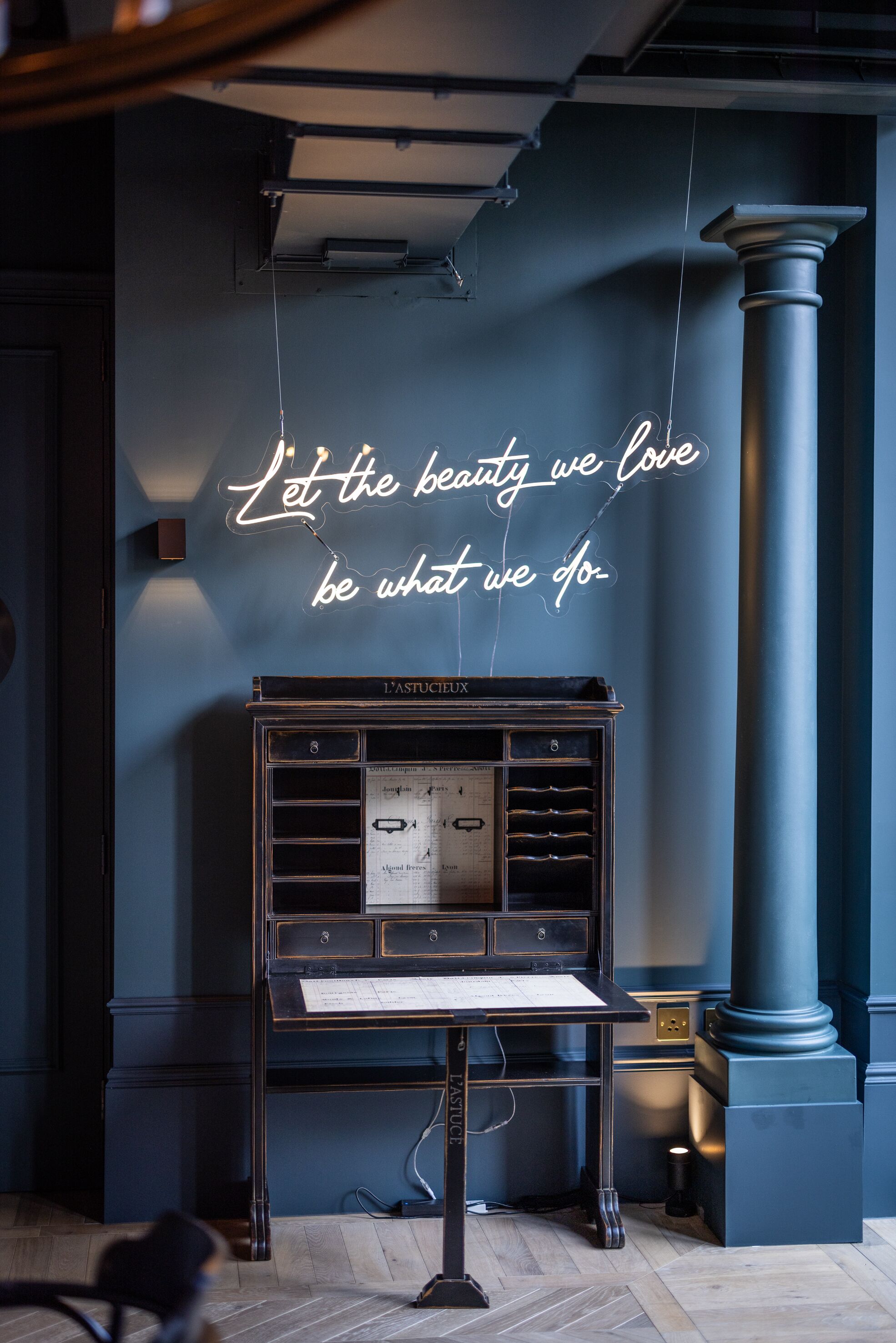 A vintage radio on a desk with a neon sign on the wall.